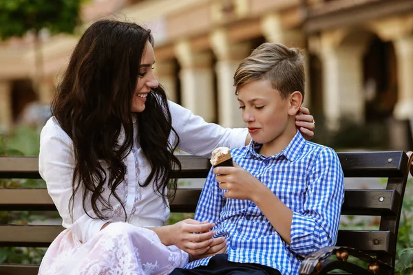 mother and son eat ice cream on the bench and have fun
