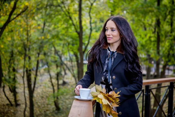 beautiful woman drinks coffee in the park