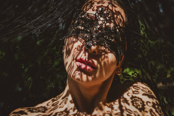 Portrait of a woman in a lace mask with shadows on her face