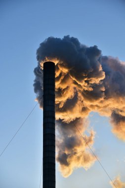 Endüstriyel baca, açık gökyüzüne karşı gün batımında.