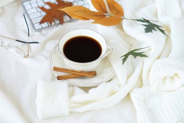 Sıcak bej pastel renkler sonbahar yaşam tarzı bileşiminde güzel. Ev çalışma alanı yatak konsepti. bir fincan kahve, örgü kazak, dizüstü bilgisayar ve sonbahar yaprakları. düz lay. 