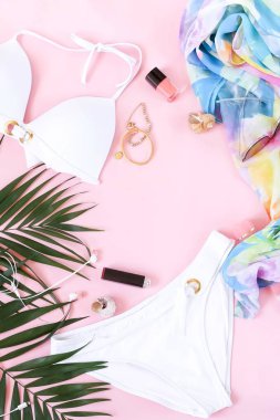 gevşeme, bir mayo, güneş gözlüğü, kadın giyim moda kolaj yapmak aksesuarları ve palmiye yaprakları soluk pembe bir arka plan üzerinde. Düz yatıyordu. üstten görünüm. Kopya alanı