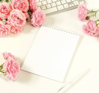 Kadınsı Ofis Masası, kadın aksesuarları, çalışma alanı ile laptop, defter ve buket güzel soluk pembe gül. Tatil kavramı. Kopya alanı