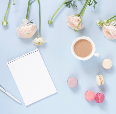 Tatil arka plan. kakao, Bademli kurabiye kurabiye pastel renkler, narin pembe tipik çiçekler ve defter soluk mavi bir arka plan üzerinde renkli bardak. Üstten görünüm. Düz yatıyordu. Kopya alanı