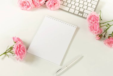 Kadınsı Ofis Masası, kadın aksesuarları, çalışma alanı ile laptop, defter ve buket güzel soluk pembe gül. Tatil kavramı. Kopya alanı