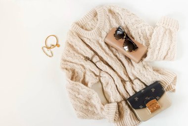Kadın moda bej renk kumaş ve aksesuarları. Mulies ayakkabı, sıcak kazak, çanta, güneş gözlüğü ile düz yatıyordu kadın rahat tarzı bakmak. Üstten görünüm. Kopya alanı