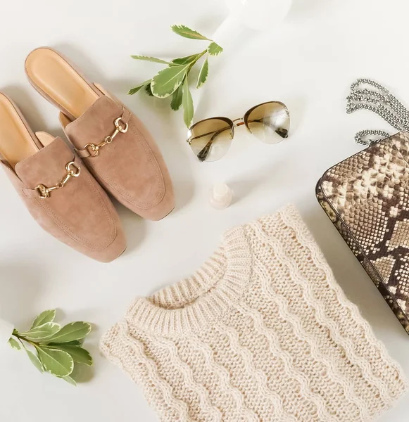 Kadın moda bej renk kumaş ve aksesuarları. Mulies ayakkabı, sıcak kazak, çanta, güneş gözlüğü ile düz yatıyordu kadın rahat tarzı bakmak. Üstten görünüm. Kopya alanı