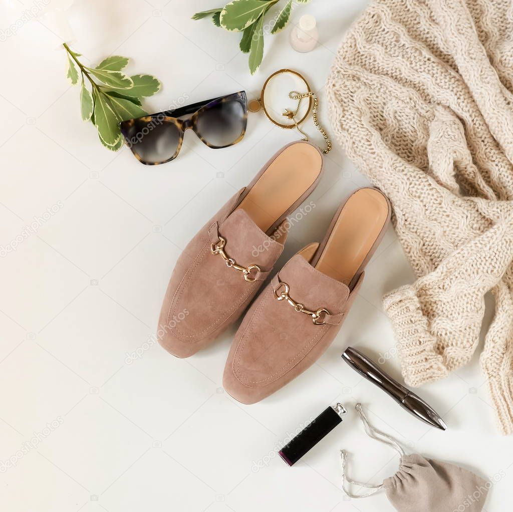 Women fashion beige color cloth and accessories. Flat lay female casual style look with mulies shoes, warm sweater, bag, sunglasses. Top view.Copy space