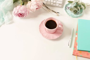 Lay kadın ofis masası düz. Kadın çalışma alanıyla laptop, çiçek peonies, aksesuarlar, defter, Gözlük, beyaz arka plan üzerinde kahve. Üstten görünüm kadınsı arka plan. Kopya alanı