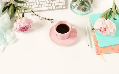 Lay kadın ofis masası düz. Kadın çalışma alanıyla laptop, çiçek peonies, aksesuarlar, defter, Gözlük, beyaz arka plan üzerinde kahve. Üstten görünüm kadınsı arka plan. Kopya alanı