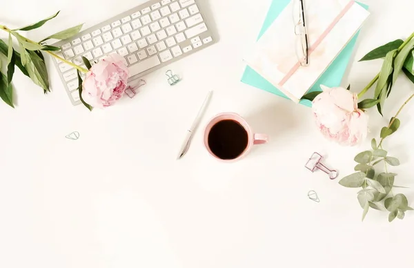 Flat lay women\'s office desk. Female workspace with laptop,  flowers peonies,  accessories, notebook, glasses, cup of coffee on white background. Top view feminine background.Copy space