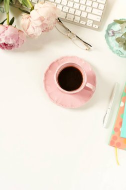 Lay kadın ofis masası düz. Kadın çalışma alanıyla laptop, çiçek peonies, aksesuarlar, defter, Gözlük, beyaz arka plan üzerinde kahve. Üstten görünüm kadınsı arka plan. Kopya alanı