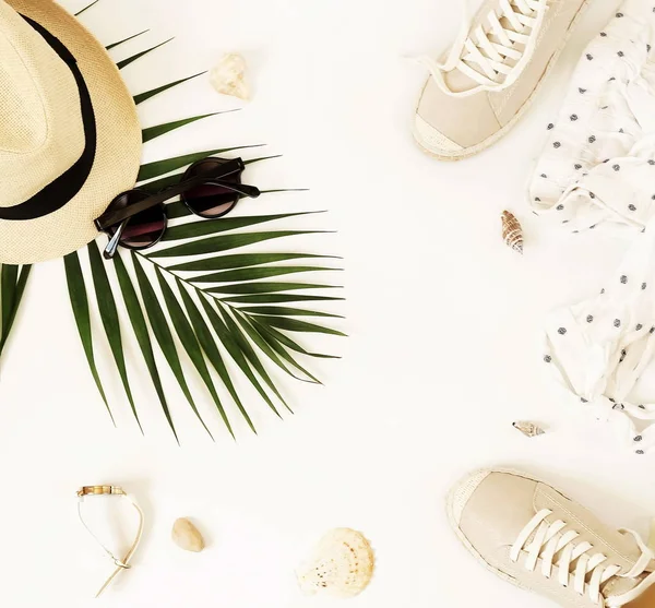 Moda arka plan. Kadın yaz giyim ve aksesuar kolaj beyaz arka plan üzerinde seyahat. Hasır şapka, spor ayakkabı espadrill, güneş gözlüğü, çanta, bluz ve palmiye yaprağı. Üstten görünüm, düz yatıyordu.