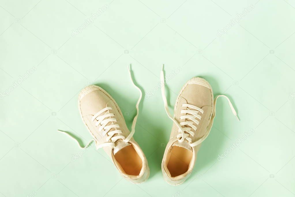 Fashion background. Beige female sneakers espadrilles on white background. Flat lay, top view minimal background.