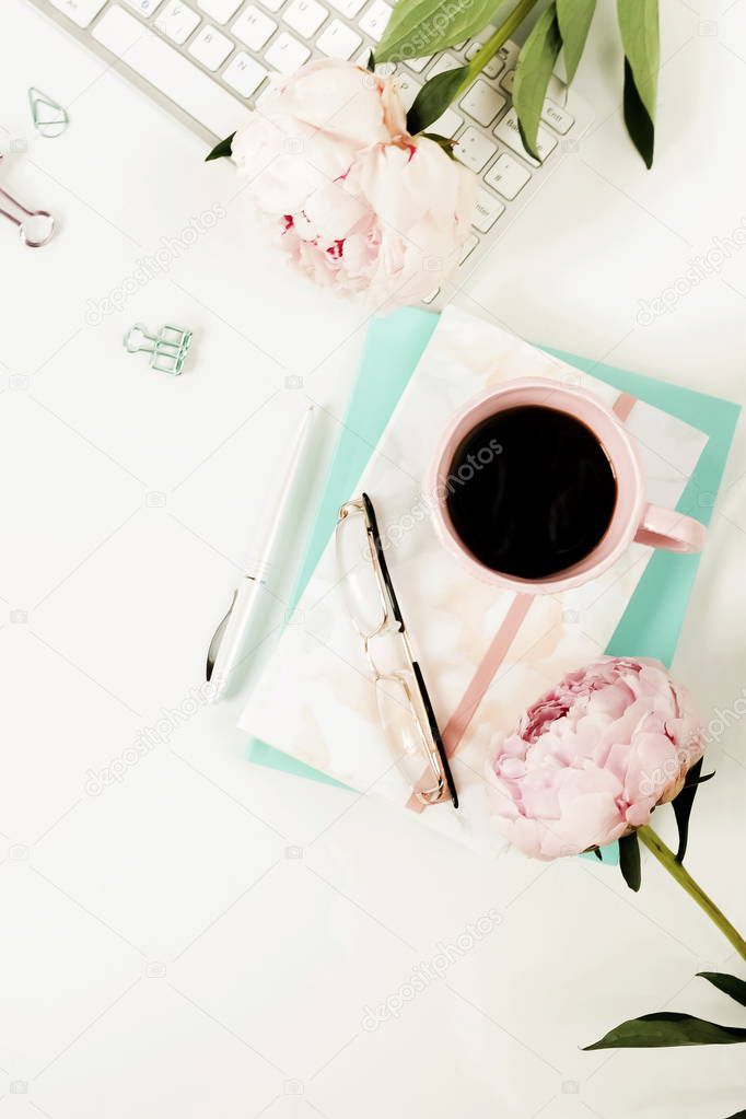 Flat lay women's office desk. Female workspace with laptop, flowers peonies, accessories, notebook, glasses, cup of coffee on white background. Top view feminine background.Copy space