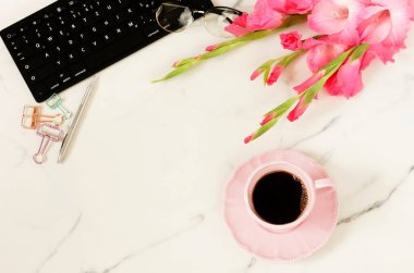 Lay kadın ofis masası düz. Kadın çalışma alanı dizüstü bilgisayar ile çiçek pembe Glayöl, aksesuarlar, Gözlük, mermer Resepsiyon arka plan üzerinde kahve. Üstten görünüm kadınsı arka plan. Kopya alanı