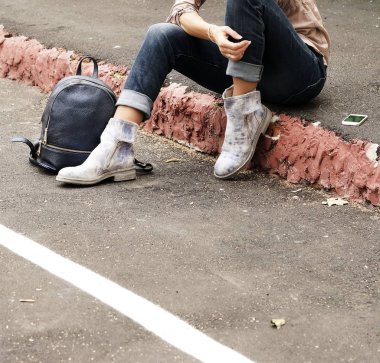 bot ile bir sırt çantası ve mobil phone.copy alanı dışında adım rahat kot pantolon giysili genç kadın oturur