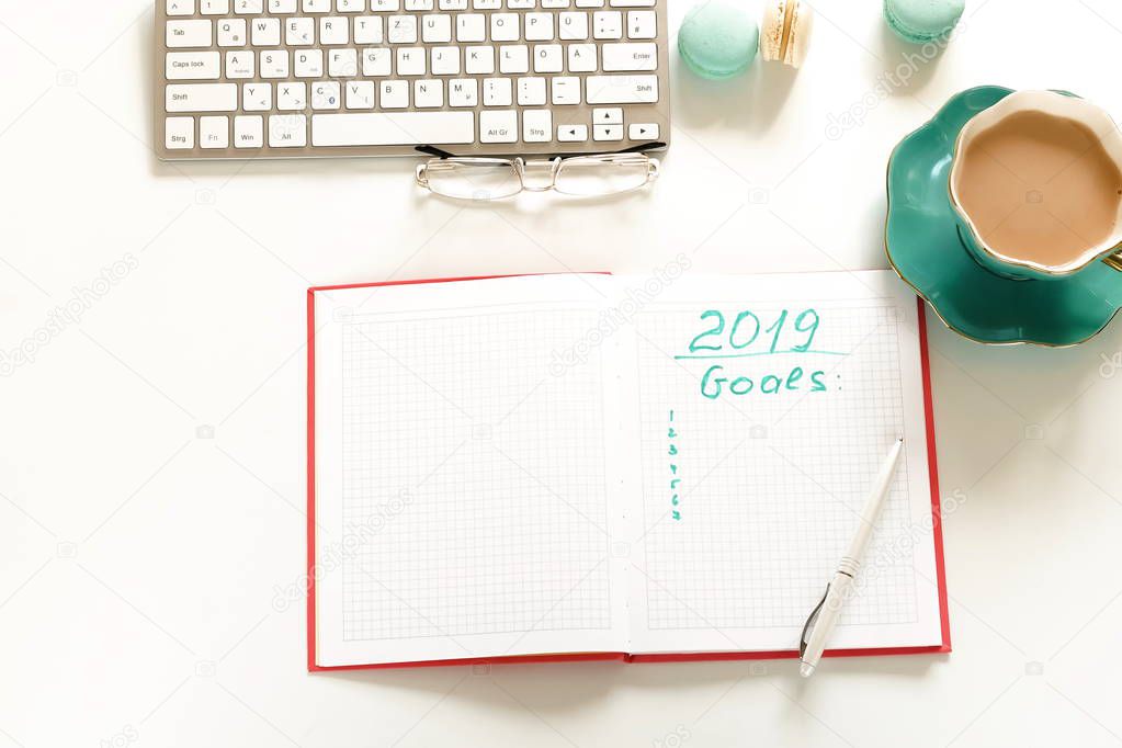 Goals 2019, To do list concept .top view, flat lay women's office desk. Female workspace with laptop, accessories, open notebook mock up, cup of cocoa on white background. Copy space. 