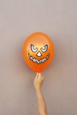 Cadılar Bayramı en az kavramı arka plan. portakal kız balonunda el duvar arka plan üzerinde. Düz yatıyordu, en iyi görünümü.