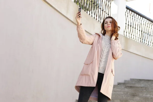 young attractive long-haired hipster girl makes a selfie on the stairs in the park