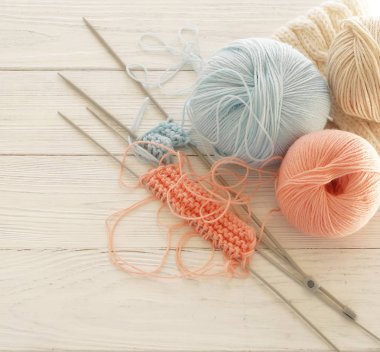 Örgü yün ve örgü iğneleri Beyaz ahşap zemin üzerinde pastel pembe ve mavi renklerde. en iyi view.copy alanı