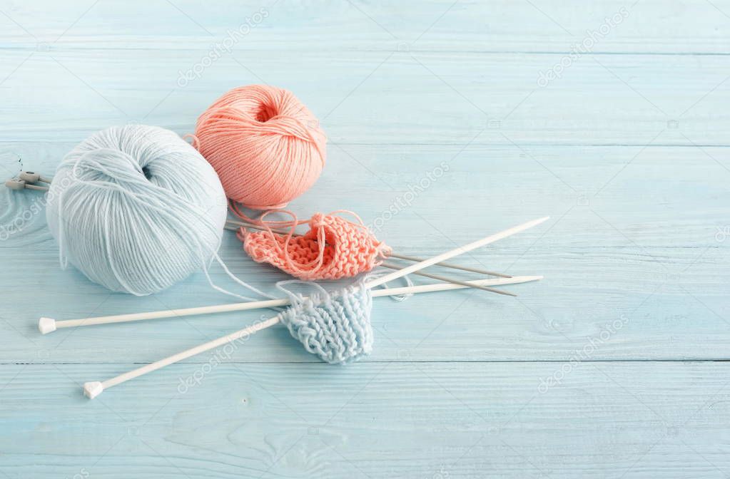 Knitting wool and knitting needles in pastel blue and pink colors on blue  wooden background. top view.copy space