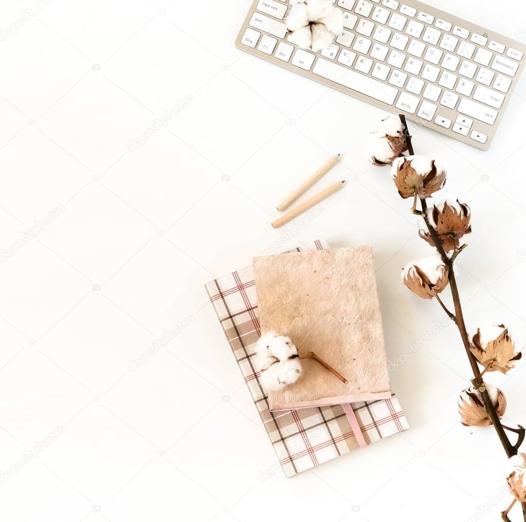 Flat lay women's office desk. Female workspace with laptop,  flowers cotton,  accessories, notebooks, glasses on white background. Top view feminine background.Copy space. 