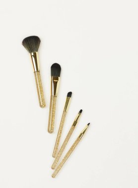 Makyaj fırçaları beyaz zemin üzerinde altın rengi ayarlayın. Profesyonel makyaj araçları. Kadın aksesuarları. Üstten görünüm. Kopya alanı