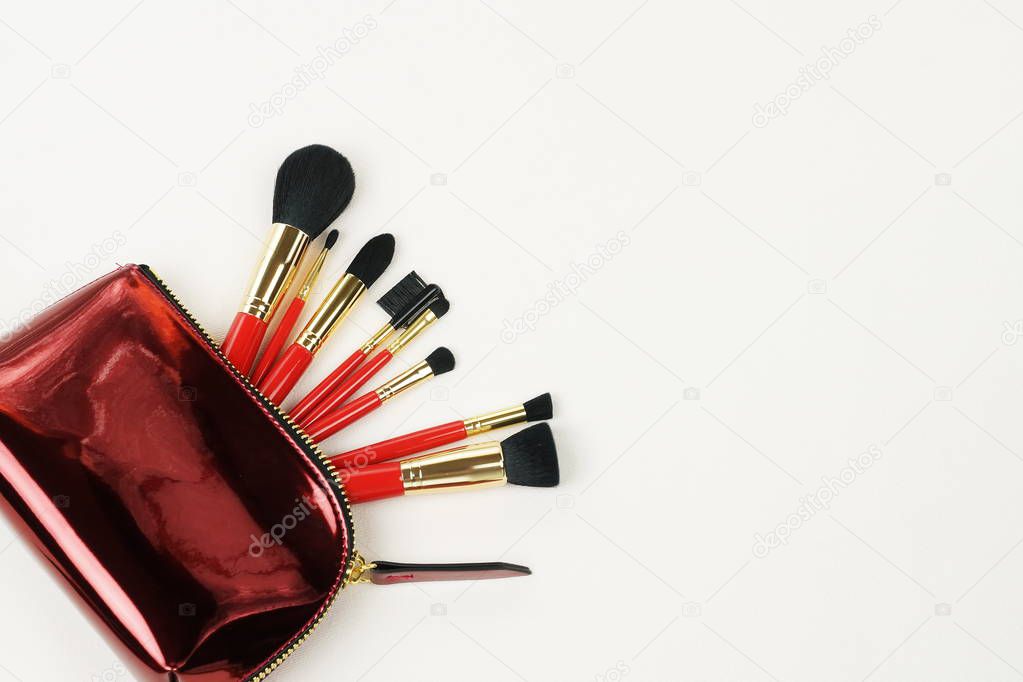 Makeup brushes set in red color in cosmetic bag on white background. Professional makeup tools . Women accessories. Top view. Copy space