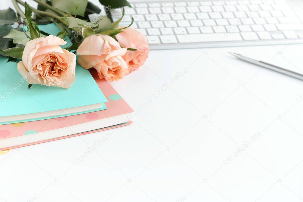 women's office desk, female workspace with laptop,  flowers roses,  accessories, notebooks on white background. Holiday background. Copy space. 