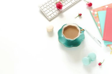 Düz yatıyordu üstten görünüm kadınların ofis masası çiçekli. Dizüstü bilgisayar, aksesuarlar, dizüstü bilgisayarlar, beyaz zemin üzerine kakao fincan ile kadın çalışma alanı. Kopya alanı