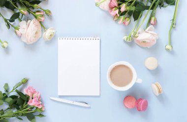 Çiçekler arka plan. Pastel renkler pembe ranunkulus çiçekler, kakao, makarna kek, defter bir alay kadar soluk mavi arka plan üzerinde. Üstten görünüm. Uzay kopyalayın. Tatil kavramı