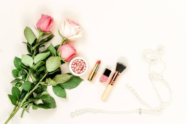 gül ve kadınsı nesnelerin ışık zemin üzerinde düzenlenmiş üstten görünüm