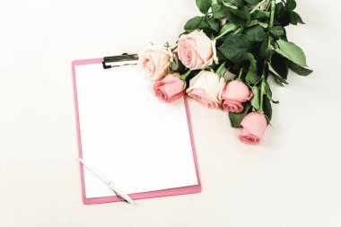 gül ve ışık zemin üzerinde düzenlenmiş boş not defteri üstten görünüm