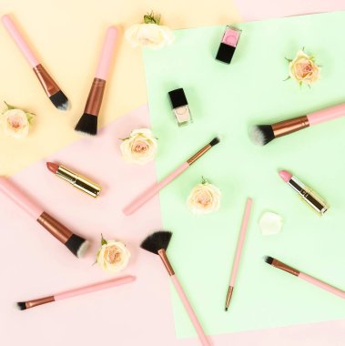 Gül ve renkli zemin üzerinde düzenlenmiş kadınsı makyaj ekipman Üstten Görünüm