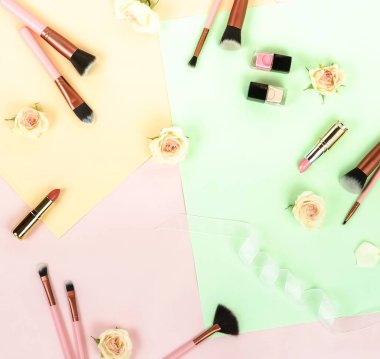 Gül ve renkli zemin üzerinde düzenlenmiş kadınsı makyaj ekipman Üstten Görünüm