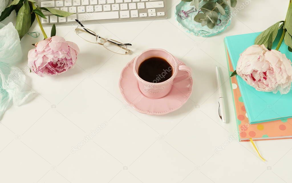 female workspace with keyboard, notebooks and cup of coffee