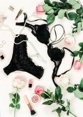 siyah iç çamaşırı, pembe güller ve beyaz zemin üzerinde makyaj malzemeleri Üstten Görünüm