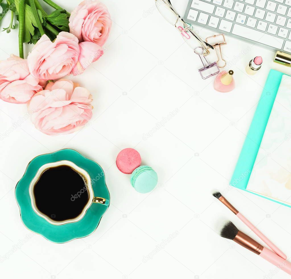 female workspace with keyboard, ranunculus flowers, macarons and cup of coffee