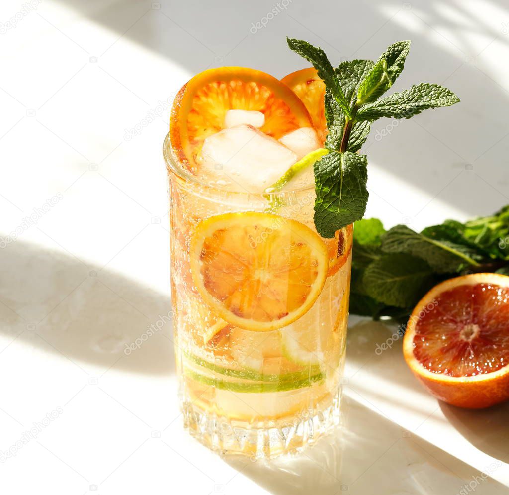 close up view of refreshing drink with ice and citrus on white backdrop