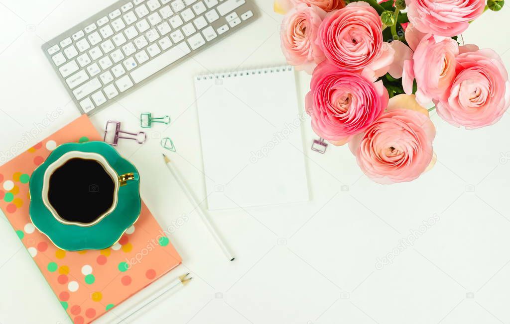 top view of female workspace with keyboard, ranunculus flowers and cup of coffee