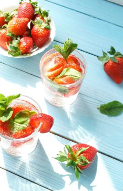 mavi ahşap yüzeyüzerinde taze çilek ile ferahlatıcı içecekler