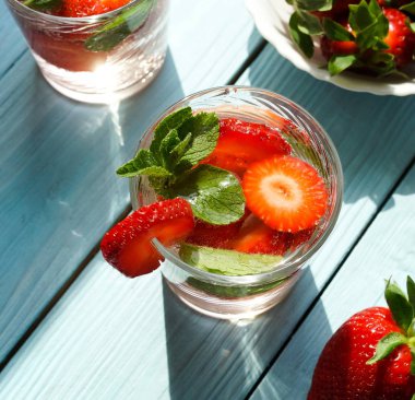 mavi ahşap yüzeyüzerinde taze çilek ile ferahlatıcı içecekler