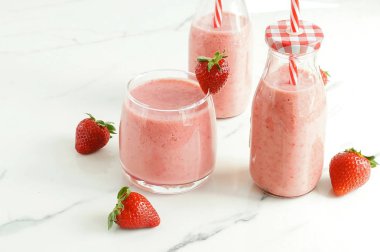 Çilek smoothie veya milkshake mermer arka plan üzerinde bir bardak. Kahvaltı ve atıştırmalık için sağlıklı yiyecekler. kopyalama alanı