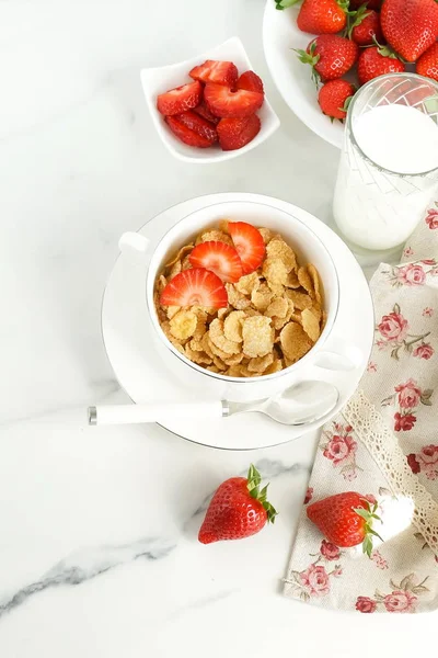 Healthy corn flakes with milk and strawberries for breakfast on marble background, desk, table.Top view. Copy space