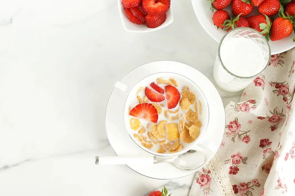 Healthy corn flakes with milk and strawberries for breakfast on marble background, desk, table.Top view. Copy space