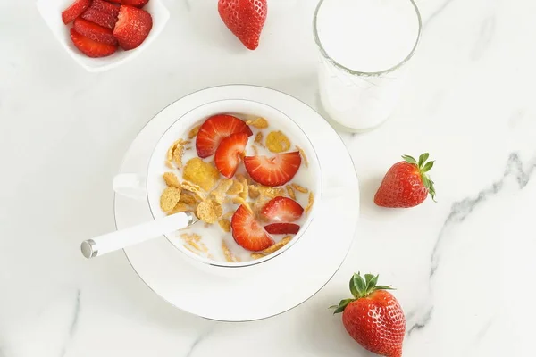 Healthy corn flakes with milk and strawberries for breakfast on marble background, desk, table.Top view. Copy space