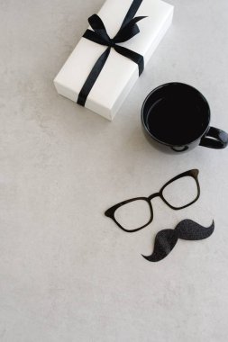 Babalar Günün kutlu olsun, kart. Komik şapka, gözlük ve bıyık, kahve fincanı, gifr veya mevcut, dizüstü gri arka plan üzerinde alay. Tonlu, klasik. Üst görünüm, Kopyalama alanı, Düz lay.