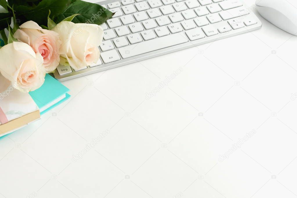 rose flowers, keyboard and notebooks on white tabletop