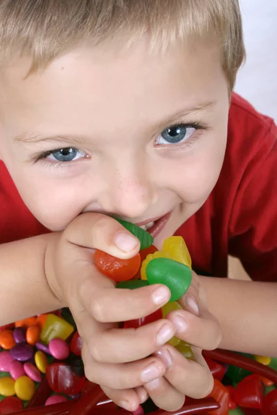 カラフルなお菓子の完全なテーブルとされている若い男の子 — ストック写真